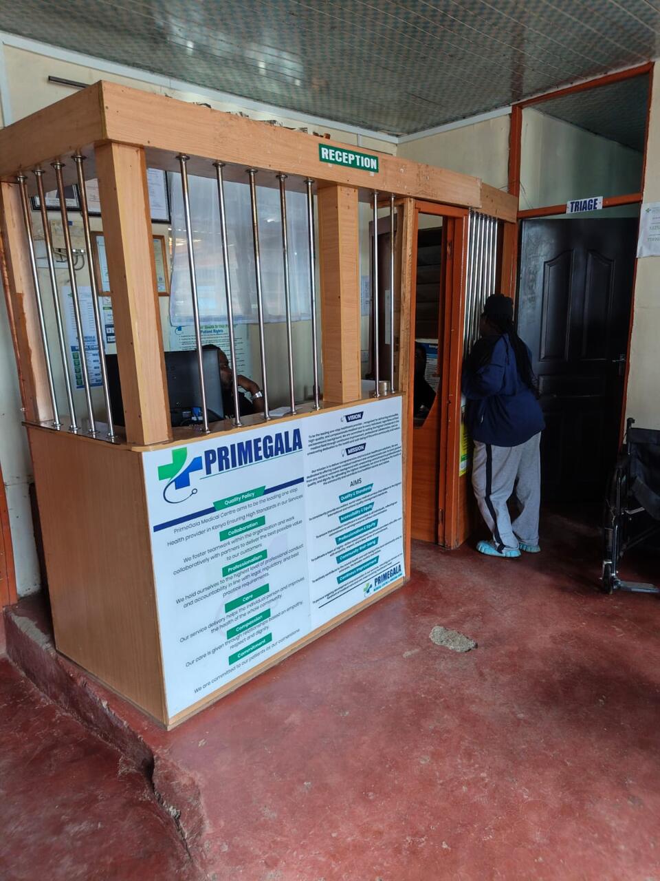 The Primegala reception desk, with the triage room door beside it and a wheelchair ready for patients
